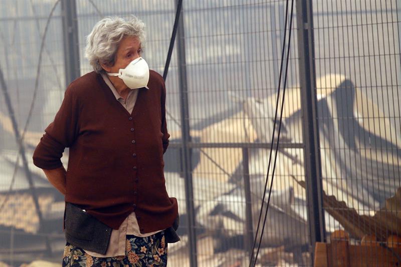 Una víctima observa el pueblo destruido por las llamas. 