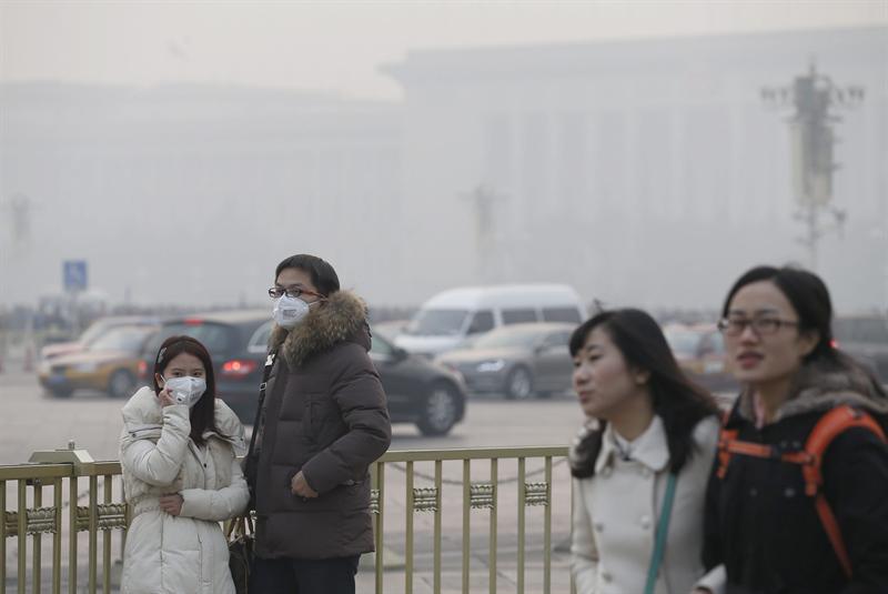 Ciudadanos de Beijing (China) con la espesa neblina al fondo.