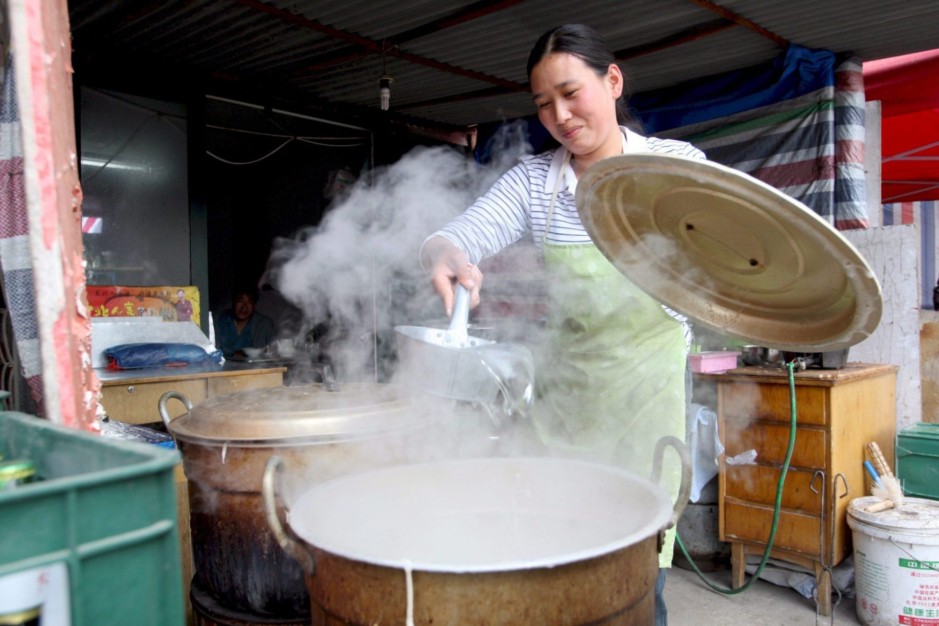 Una mujer cocina fideos en un pequeño restaurante.