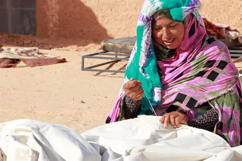 Samiha cosiendo su tienda de campaña para vivir después de que su casa fuera destruida por las lluvias.