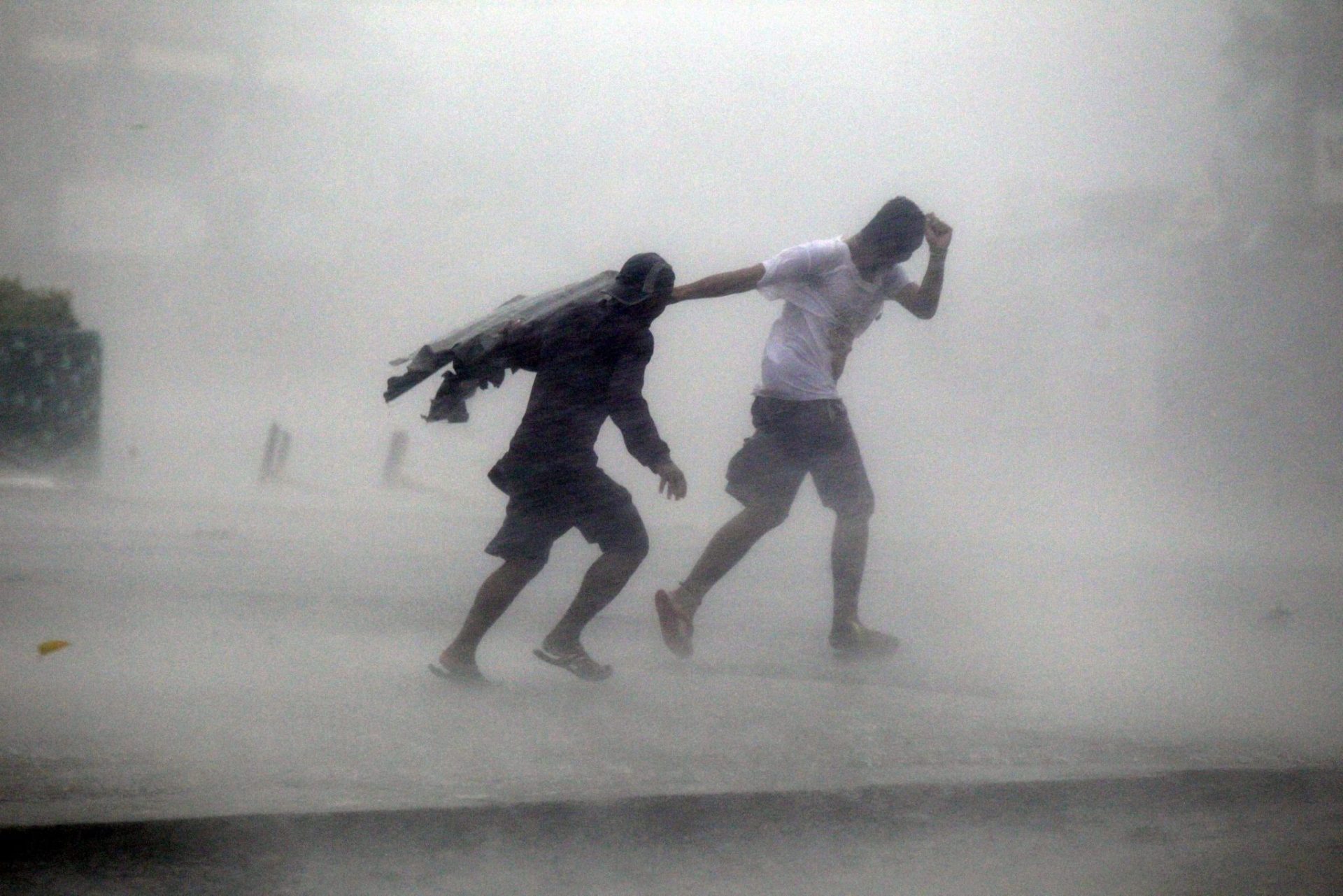 Esfuerzos de dos viandantes para caminar bajo la lluvia y contra el viento.