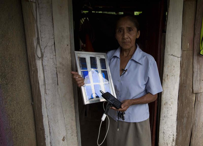 María Muñoz, de 65 años, sostiene un cargador para celulares que ella construyó a base de paneles solares. 