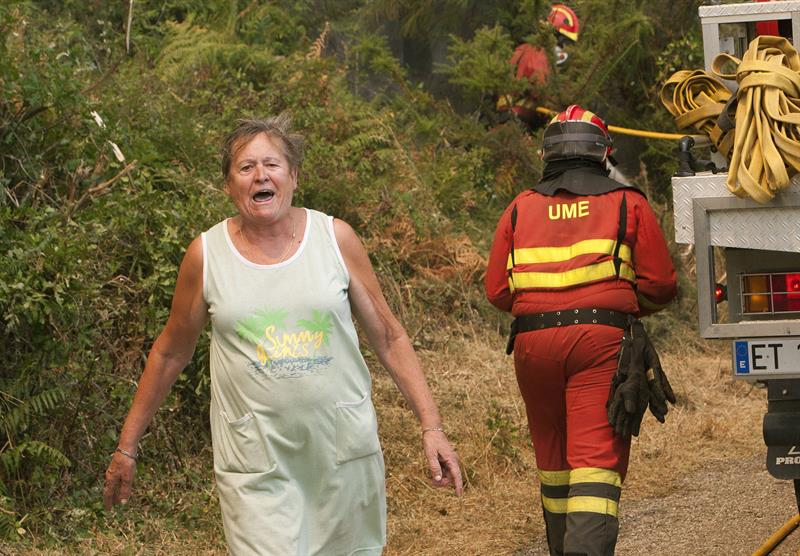Expresión de enfado de una señora junto a los bomberos que luchan contra el fuego en Arbo (Pontevedra).