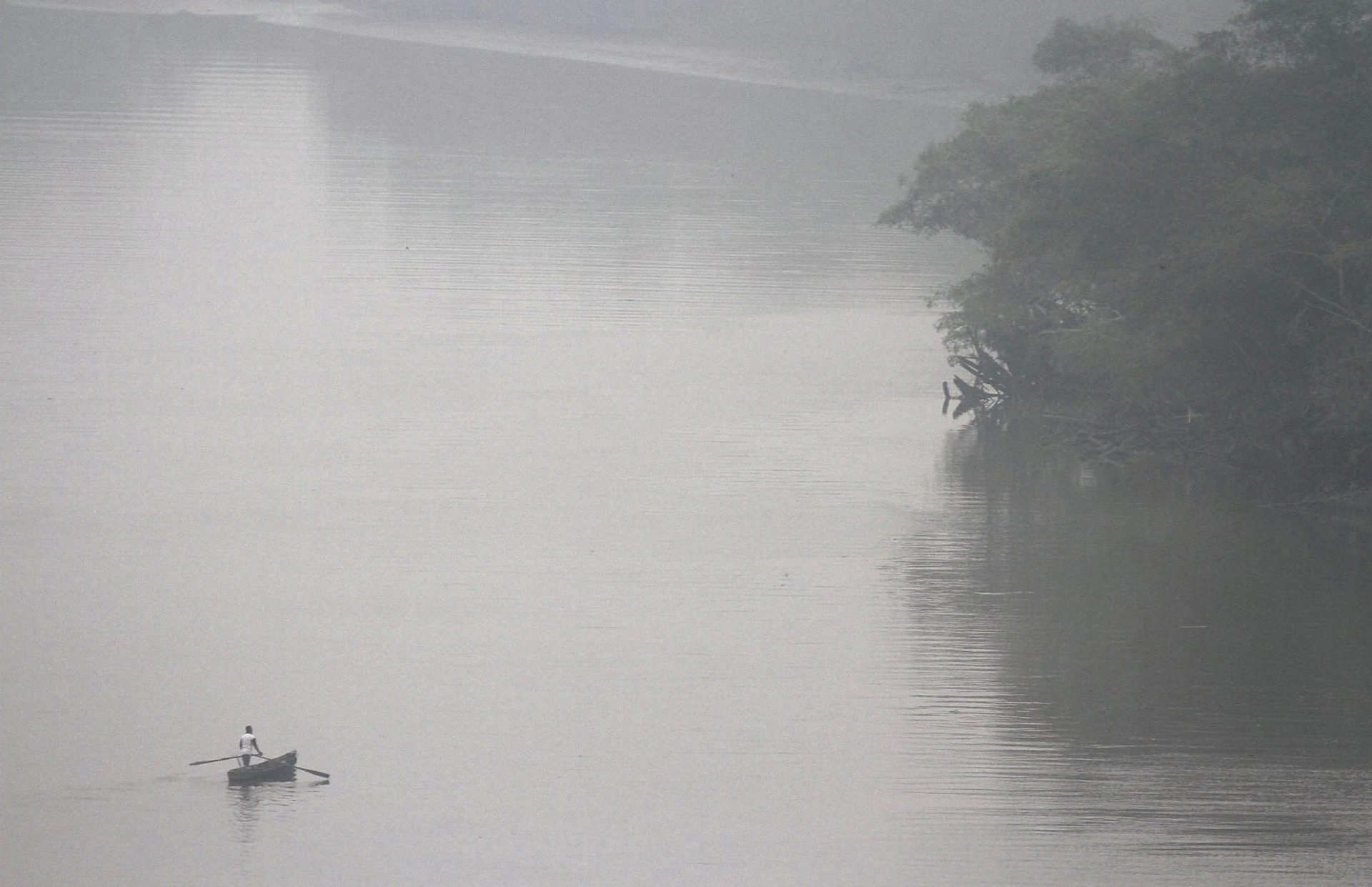 Una canoa por el río Siak en medio de una espesa niebla en Riau.