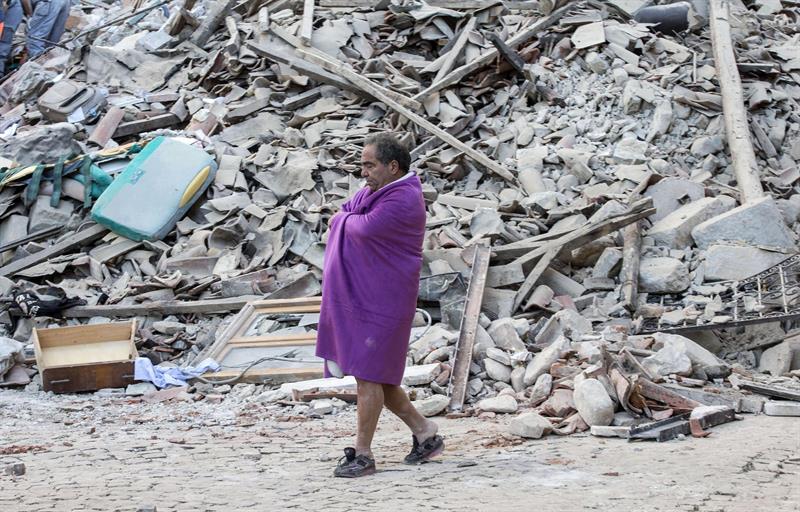 Un hombre camina entre los escombros de varios edificios en Amatrice, en el centro de Italia. Al menos 19 personas han fallecido y hay decenas de heridos tras el terremoto de 6 grados en la escala Richter que ha sacudido el centro de Italia esta madrugada, según la televisión pública RAI. 