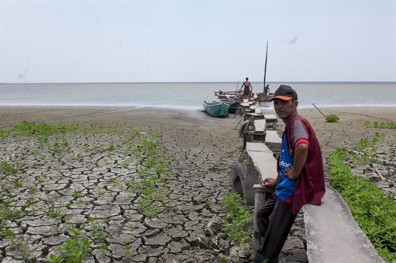La retirada del agua obliga a los pescadores a arrastrar las lanchas de fabricación artesanal hasta el agua y a veces se queda pegada entre el fango y los sedimentos.  