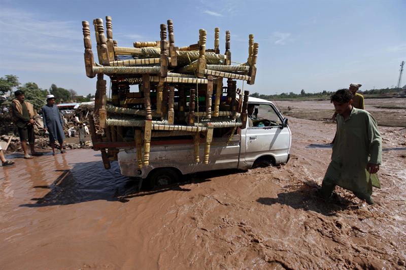 Una furgoneta transporta enseres en medio de una calle inundada en Peshawar. 