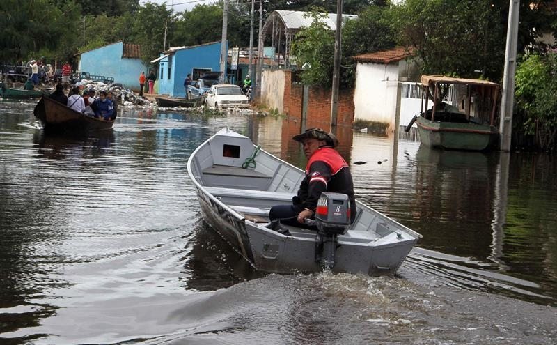 Un paraguayo conduce una barca a motor por una de las calles inundadas del barrio Tacumbú , en Asunción (paraguay) tras la crecida del río del mismo nombre.