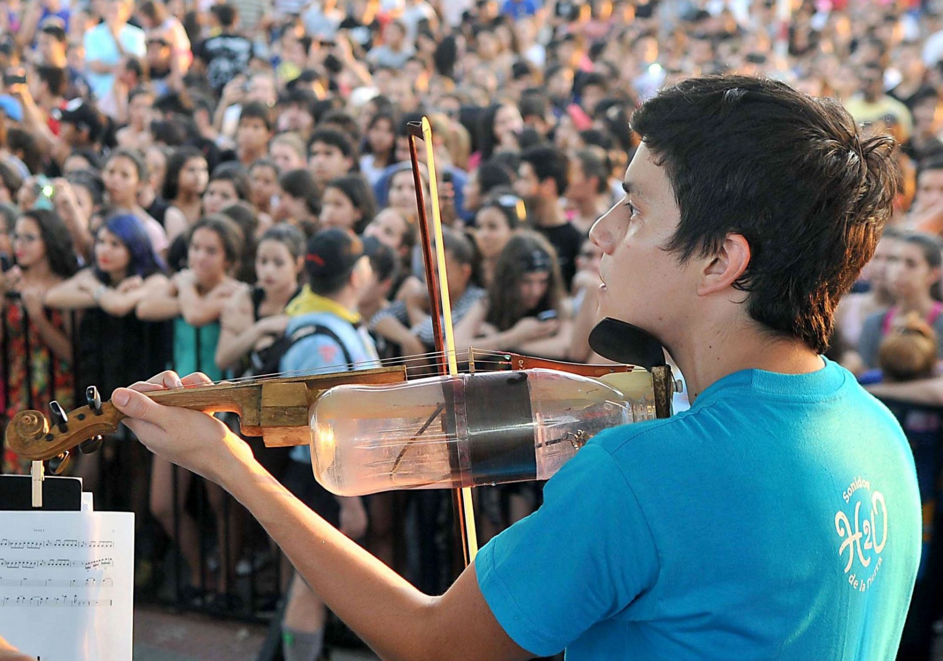 Un músico interpreta un instrumento hecho con una botella de plástico reciclada.