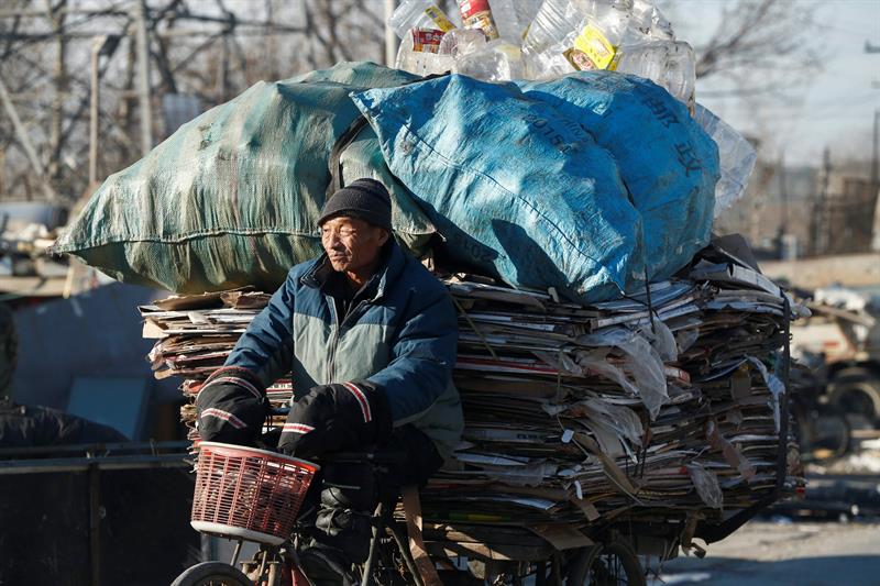 Un reciclador traslada cartones en su motocarro en el distrito de Changping en Pekín