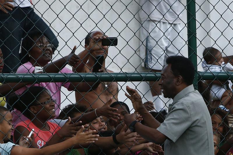 RÍO DE JANEIRO (BRASIL), 10/09/2014.- El exjugador brasileño Edson Arantes do Nascimento 'Pelé' saluda hoy, miércoles 10 de septiembre de 2014, durante la presentación de una cancha de última generación en la favela Morro da Mineira, en Río de Janeiro (Brasil). El campo de fútbol usa placas cinéticas para aprovechar el movimiento de los jugadores y así generar su propia iluminación. EFE/Marcelo Sayão