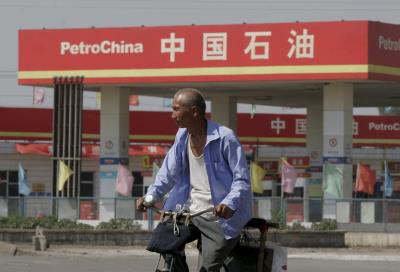 Un hombre corre bicicleta frente a la estación de gas PetroChina. EFE/QILAI SHEN