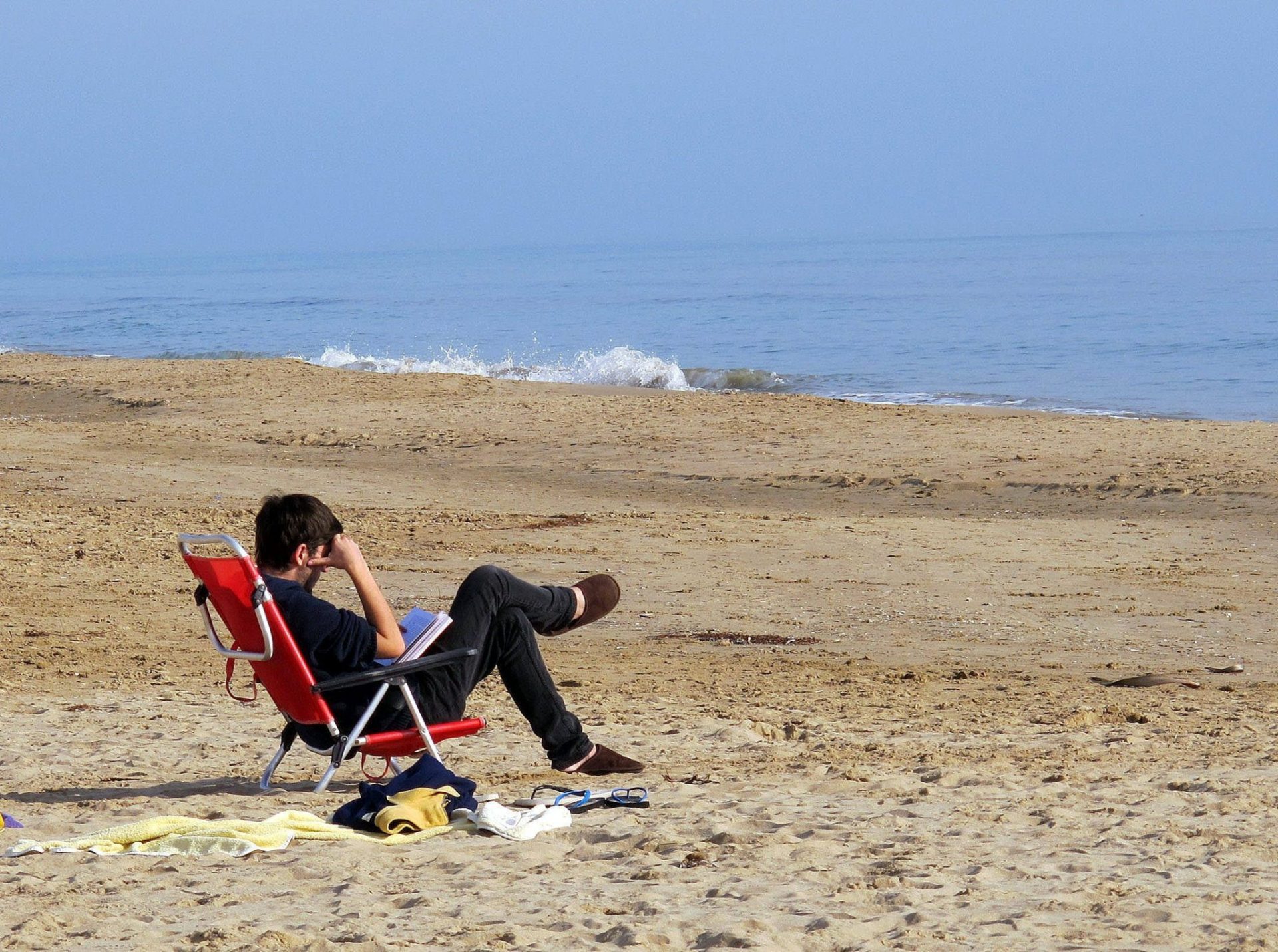 Un chico lee en la playa de Torredembarra (Tarragona).