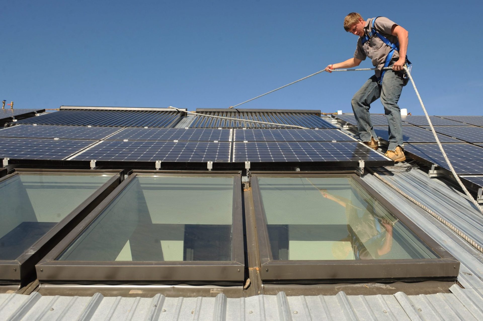 Un operario coloca paneles solares en una vivienda.