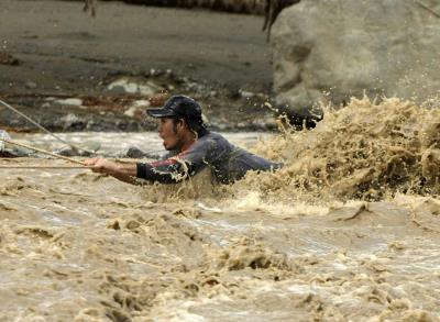 Un miembro de los equipos de rescate utiliza una cuerda para cruzar el agua de las inundaciones durante un rescate en New Bataan (Filipinas), en diciembre de 2012.