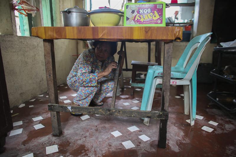 Conception Roseth, una viuda filipina de 71 años, muestra cómo se protegió con su nieto y su hermana durante cinco horas el paso de Haiyan, bajo una mesa de la cocina de su casa en Guiuan (Isla de Samar).