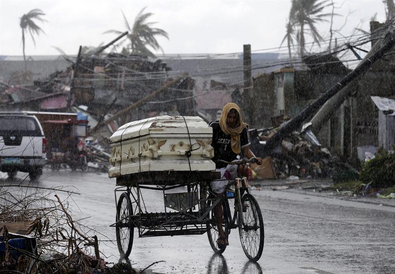 Un filipino transporta en bici el ataúd de un familiar bajo la intensa lluvia en Tacloban (Filipinas) hoy, 19 de noviembre de 2013.