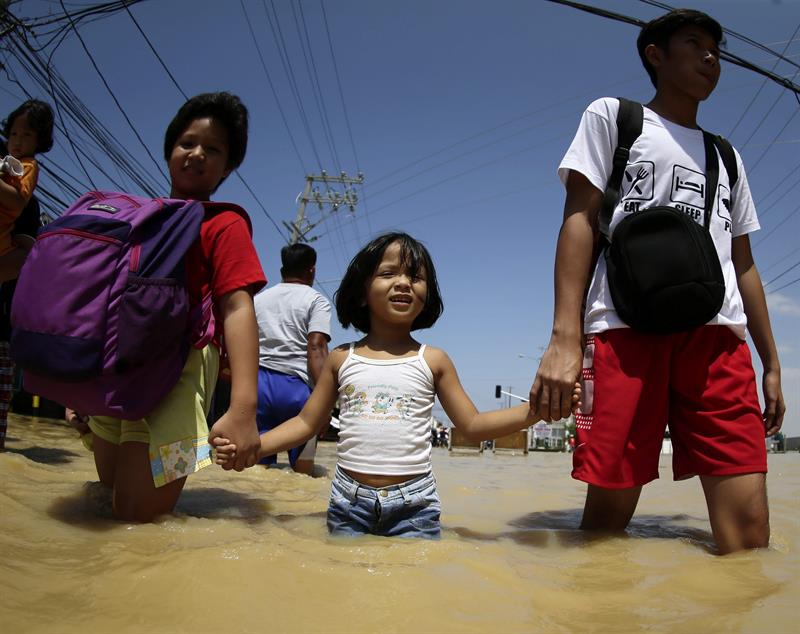 Niños caminan por una calle inundada de Calumpit tras el paso del tifón Koppu. 