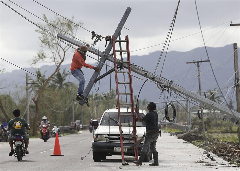 Operarios filipinos reparan un poste caido por el paso del tifón Nock-Ten por la localidad de Polangui, provincia de Albay (Filipinas). 
