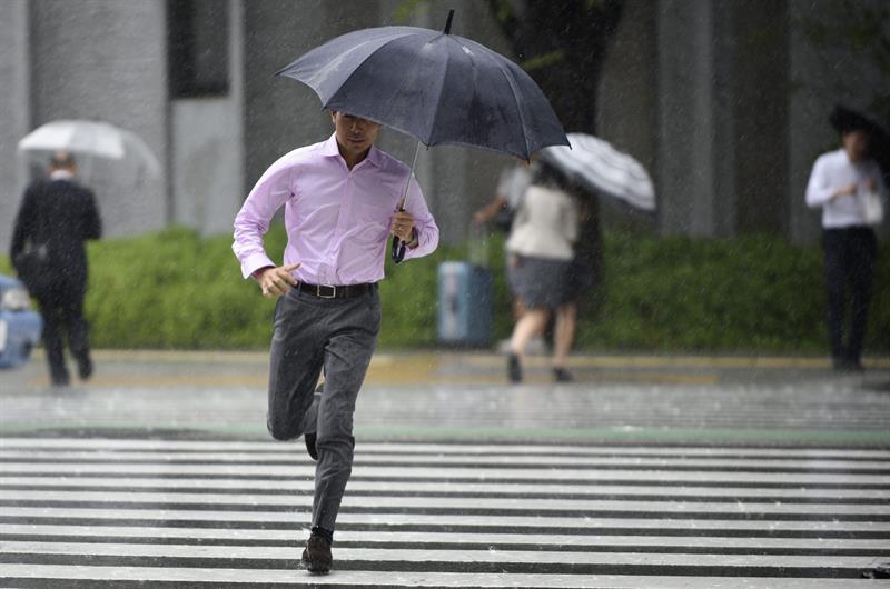 Un peatón cruzan corriendo una calle bajo la lluvia provocada por el tifón Etau en Tokio.