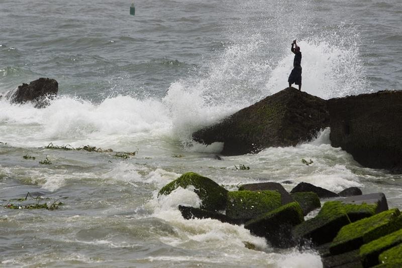 Un hombre pesca en el malecón en Santo Domingo, con un fuerte oleaje.