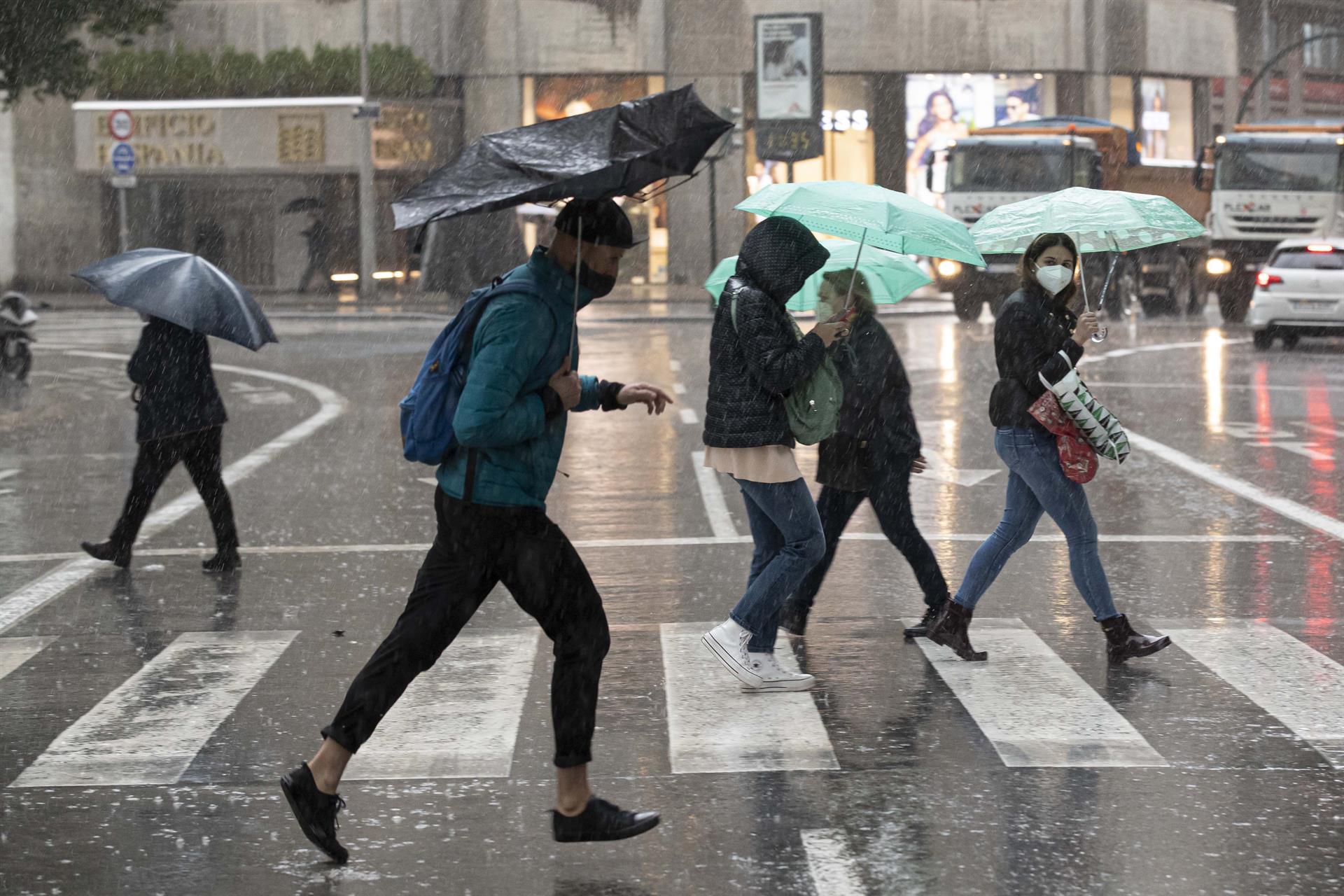 Varias personas se resguardan de la lluvia en la Gran Vía de Murcia. EFE/Marcial Guillén