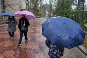 Imagen de archivo. Dos personas pasean con paraguas bajo la lluvia.
