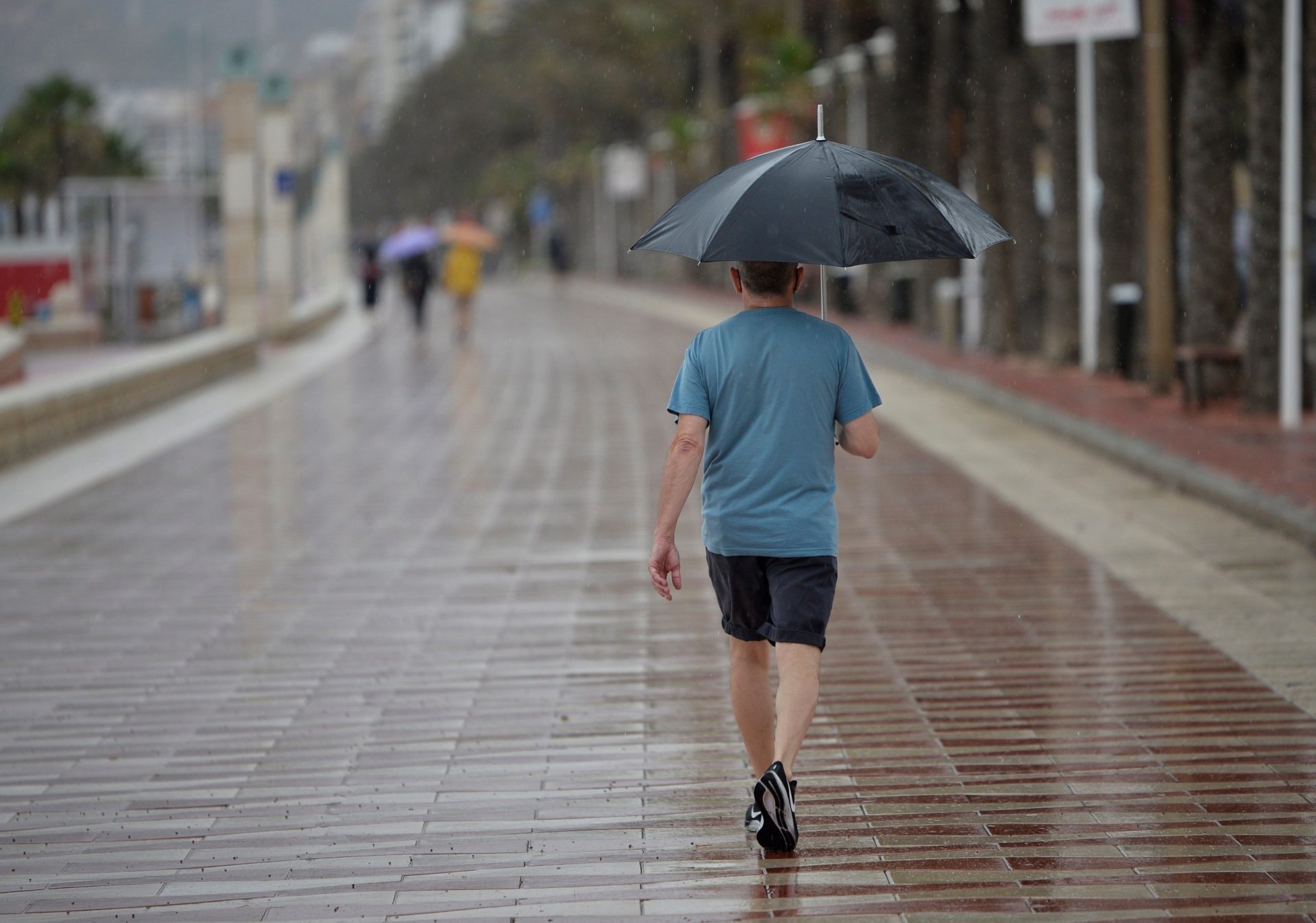 Foto de archivo. Un hombre camina bajo la lluvia por el Paseo Maritimo de Almería. EFE / Carlos Barba