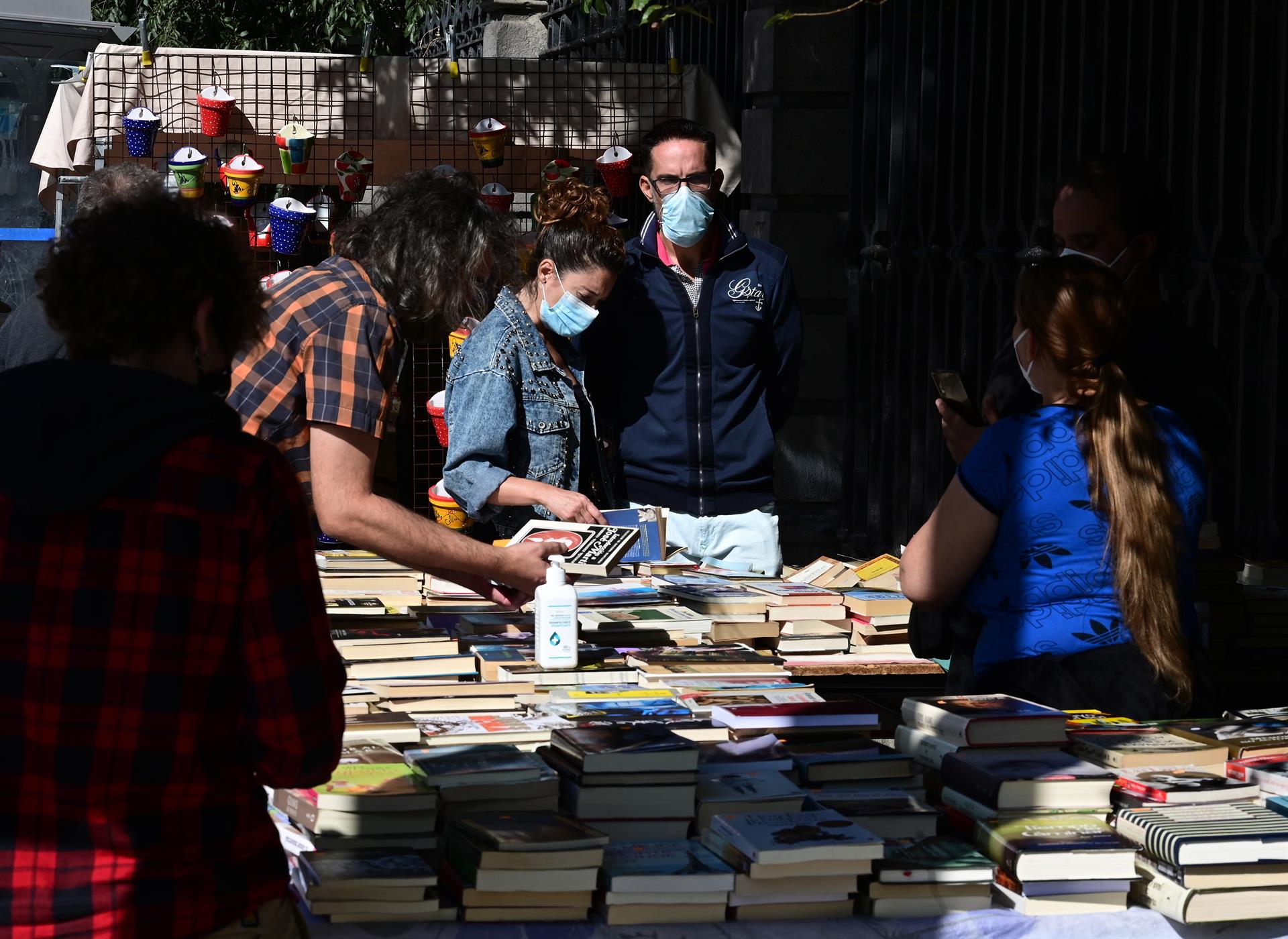 varios clientes ojean libros de segunda mano en uno de los puestos del Rastro, en Madrid. EFE/Víctor Lerena