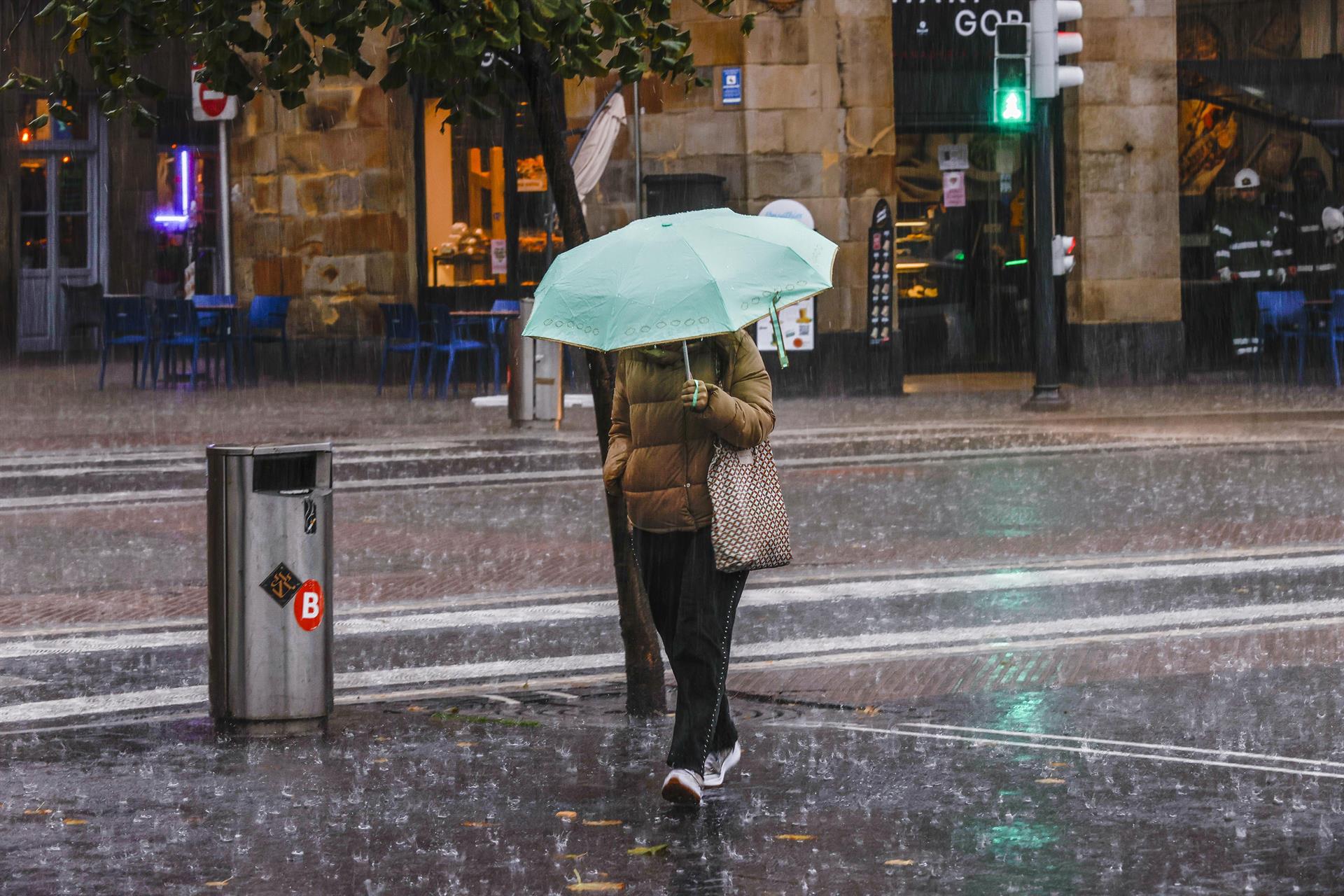Una mujer camina bajo un fuerte aguacero en Bilbao este lunes. EFE/Miguel Toña