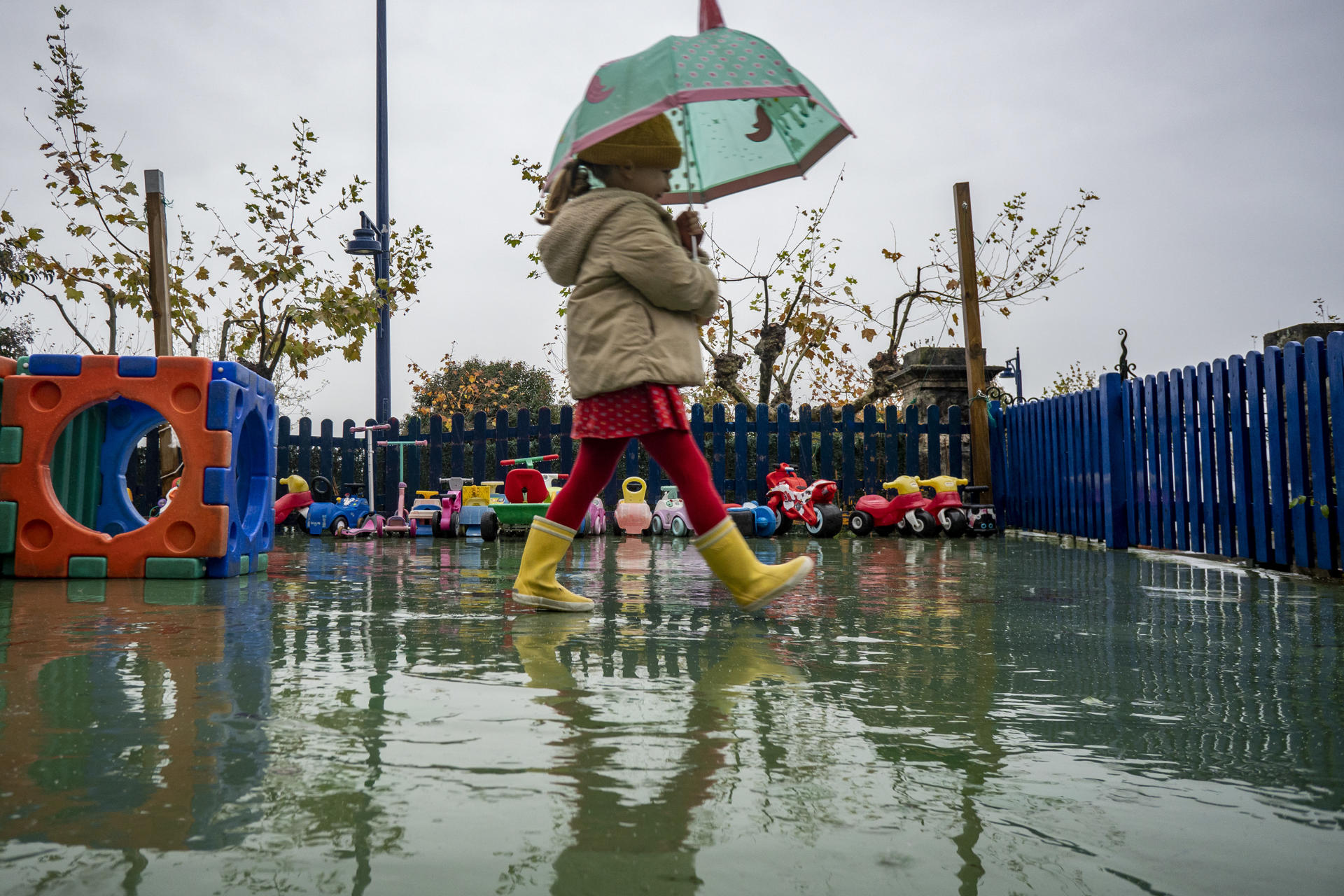 Una niña se protege de la lluvia bajo un paraguas en el patio del colegio en Santander, este lunes. EFE/Román G. Aguilera