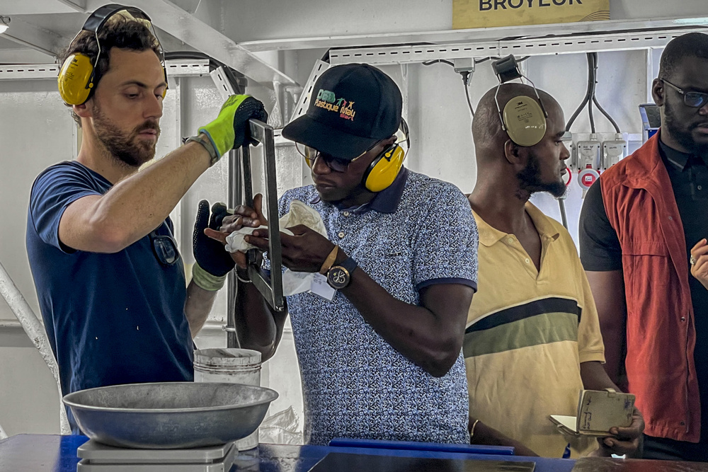 DAKAR (SENEGAL), 01/03/2023.- Un miembro del equipo de Plastic Odyssey y un emprendedor africano durante la explicación de una de las máquinas a bordo del barco Plastic Odyssey para la formación y transmisión de conocimiento a empresarios del países del sur con el objetivo de valorizar los plásticos usados creando objetos útiles el pasado 22 de febrero. EFE/ María Rodríguez