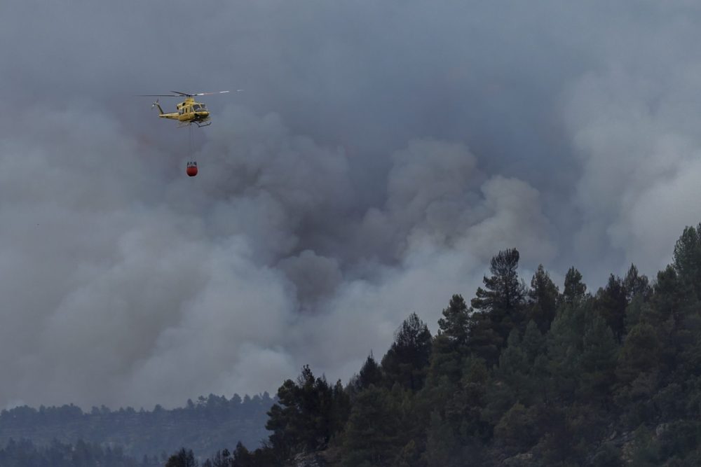 Un helicóptero sobrevuela la columna de humo del incendio forestal declarado ayer en el término municipal de Villanueva de Viver, en la zona limítrofe de las provincias de Castellón y Teruel. EFE/Manuel Bruque