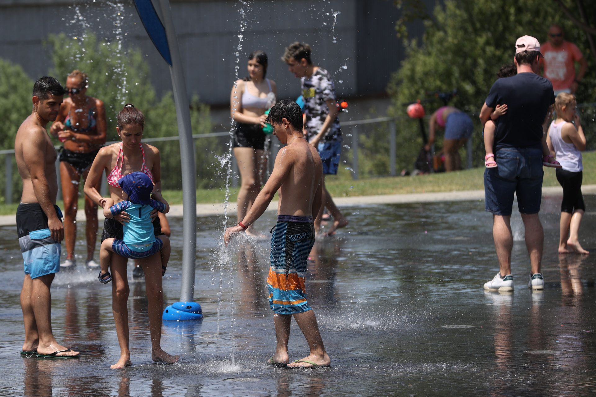 GRAF1143. MADRID (ESPAÑA), 09/07/2023.- Niños y adultos se refrescan en las fuentes públicas de la capital en una jornada marcada por las altas temperaturas. Con unas temperaturas en progresivo aumento en buena parte del país a las puertas de una nueva ola de calor, siete comunidades del sur y este del país están este domingo en alerta por valores de hasta 40 grados, especialmente Castilla-La Mancha y Andalucía, con amplias zonas en nivel de riesgo importante o naranja. EFE/ Kiko Huesca