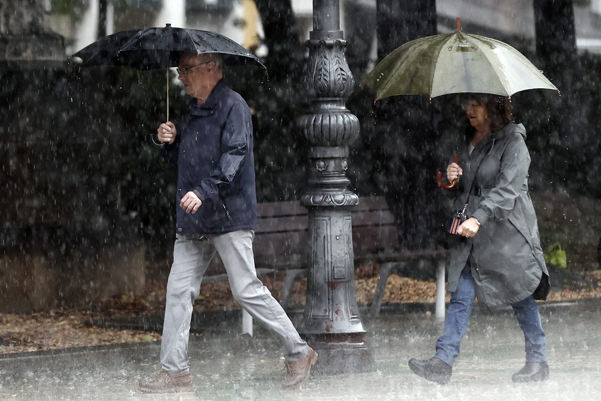Dos personas se protegen de la lluvia con sus paraguas en una jornada donde el ambiente inestable, con chubascos localmente fuertes y de cierta intensidad continúa en la Comunidad Foral. EFE/ Jesús Diges