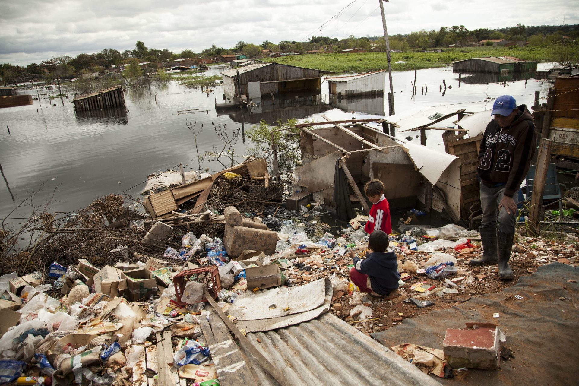 Imagen de archivo que muestra a varias personas cerca a una zona inundada en unos de los campamentos de desplazados de Asunción. EFE/Santi Carneri