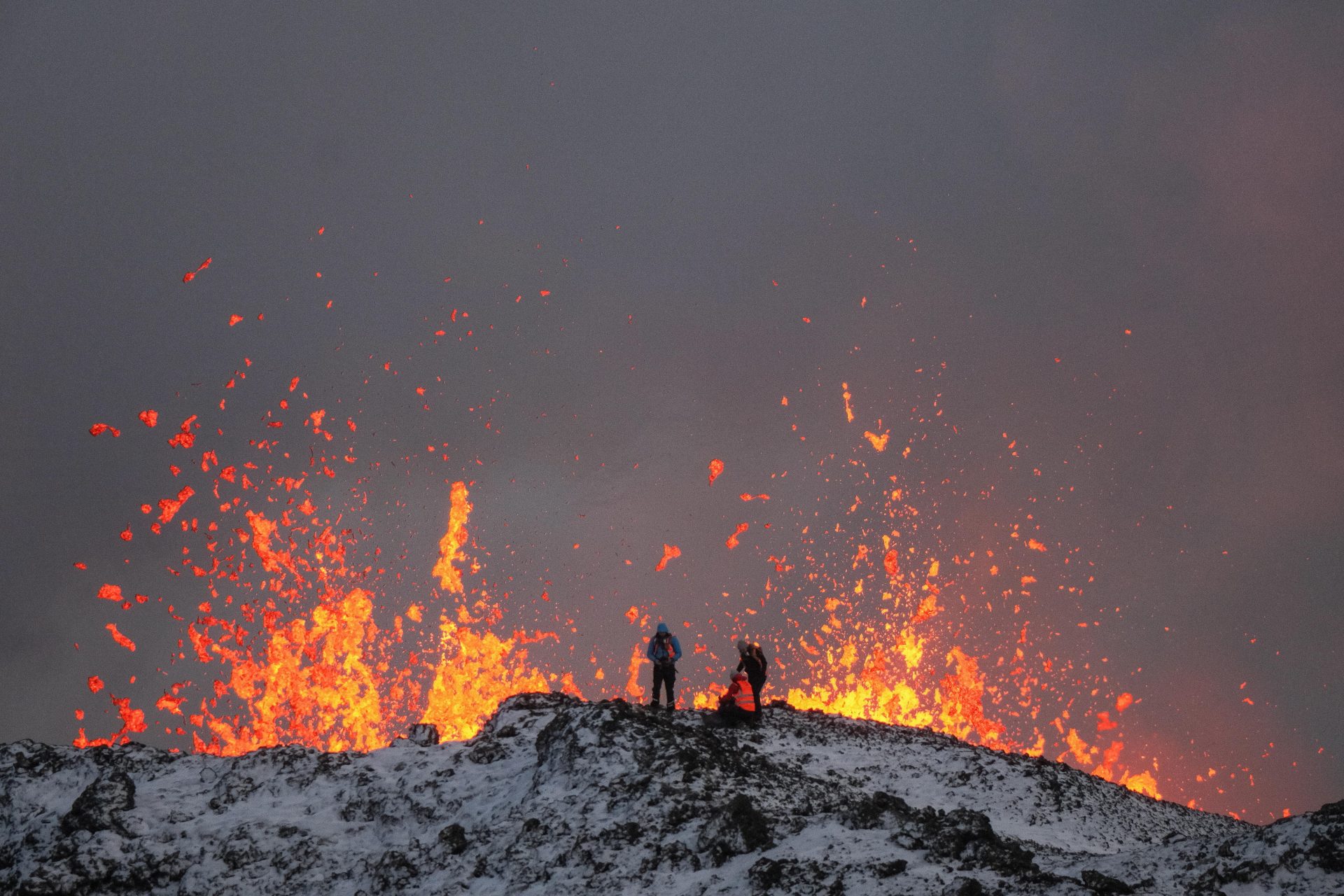 -FOTODELDÍA- EA2876. GRINDAVIK (ISLANDIA), 19/12/2023.- Un equipo de científicos trabaja hoy, en la cresta de una fisura volcánica mientras sale lava durante una erupción volcánica, cerca de la ciudad de Grindavik, en la península de Reykjanes (Islandia). La Oficina Meteorológica de Islandia (OMI) anunció el inicio de una erupción volcánica fisural cerca del cráter de Sundhnuka, al noreste de Grindavik, en la noche del 18 de diciembre, tras semanas de intensa actividad sísmica en la zona. La potencia y la actividad sísmica de la erupción han disminuido con el tiempo, informó la OMI el 19 de diciembre, añadiendo que se han registrado unos 320 seísmos desde el inicio de la erupción. EFE/EPA/ANTON BRINK