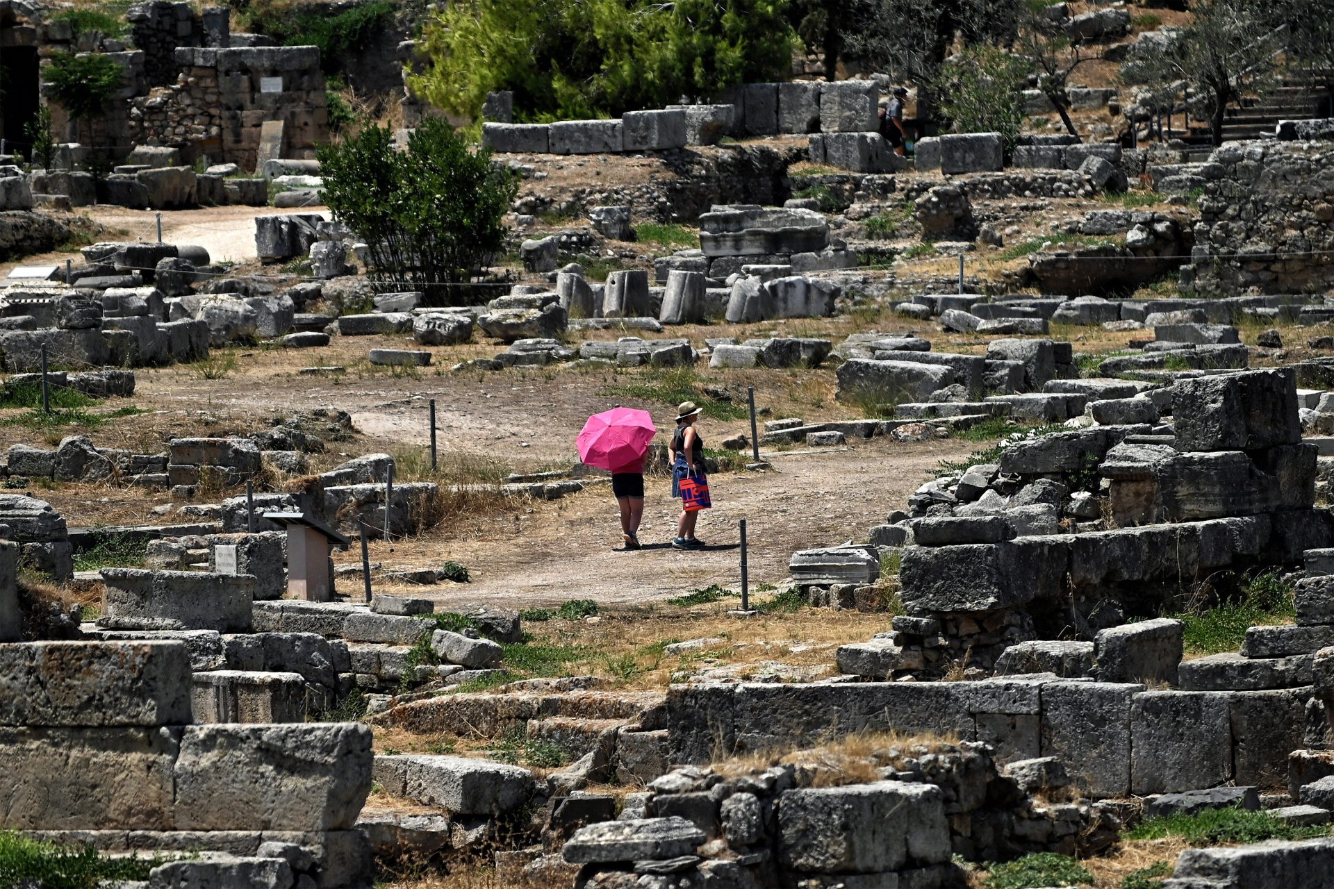 Corinth (Greece), 14/07/2024.- Tourists visit the archaeological site of Ancient Corinthe holding umbrellas, to protect themselves from the strong sun, Greece, 14 July 2024. A prolonged heatwave is affecting Greece with high temperatures expected to reach up to 43 degrees Celsius and persisting at least until 19 July. (Grecia) EFE/EPA/VASSILIS PSOMAS