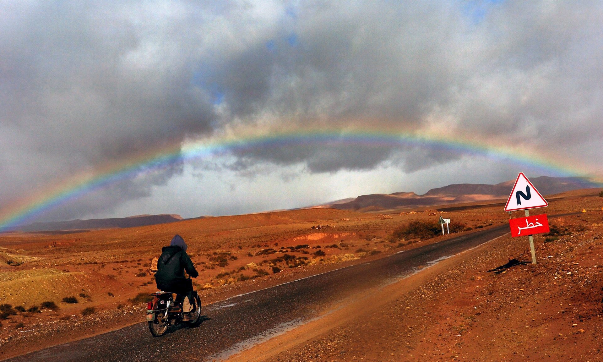 VAS08. OUARZAZATE (MARRUECOS), 09/01/08.- Un motociclista contempla el arcoiris en el desierto del Sáhara, cerca de la ciudad de Ouarzazate, en Marruecos, el 4 de enero de 2008. Ouarzazate es una ciudad que mezcla diferentes culturas y se encuentra en mitad del desierto y es la puerta de uno de sus oasis. La ciudad también es conocida entre los turistas por su belleza. EFE/Vassil Donev