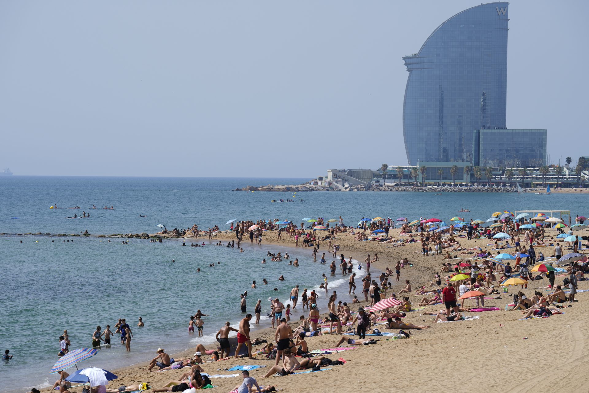 GRAFCAT2352. BARCELONA, 10/07/2023.- Aspecto de la playa de la Barceloneta de Barcelona este lunes en plena ola de calor intenso en Cataluña, con la previsión de que los termómetros superen los 40 grados en el interior entre este lunes y el martes, por lo que los médicos recomiendan hidratarse constantemente, refrigerar la casa, aplicar toallas mojadas sobre el cuerpo y no exponerse al sol para evitar que las personas, especialmente las mayores y con patologías, puedan acabar en el hospital por un golpe de calor. EFE/Alejandro García