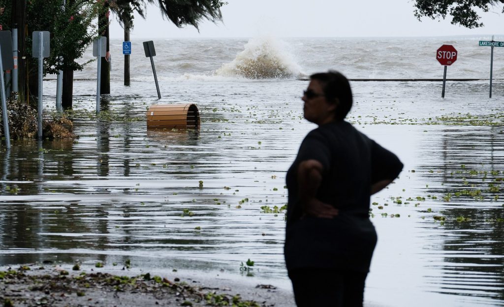Fotografía de archivo de una mujer frente a una carretera inundada cerca del lago Pontchartrain, en Estados Unidos, mientras se aproxima un huracán EFE/ DAN ANDERSON