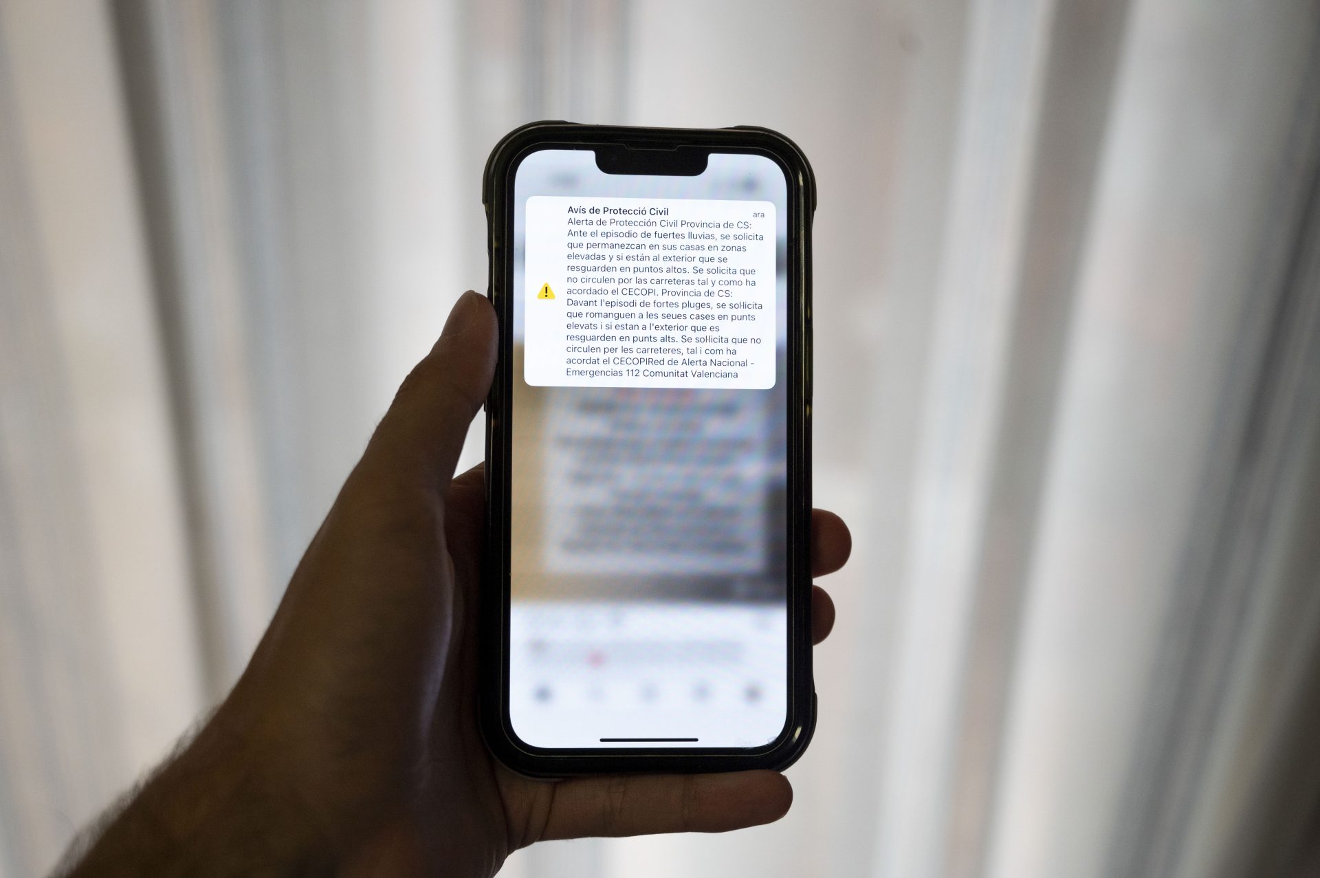 Una persona muestra en su móvil el aviso de protección civil para la provincia de Castellón en el que se pide que las personas se resguarden en puntos altos tanto en sus casa como si se encuentran en el exterior y que no se circule por las carreteras. EFE/ Andreu Esteban