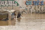 Dos personas vadean un terreno de chabolas inundado junto a la V-30 a causa de las lluvias torrenciales de las últimas horas. EFE/Biel Aliño