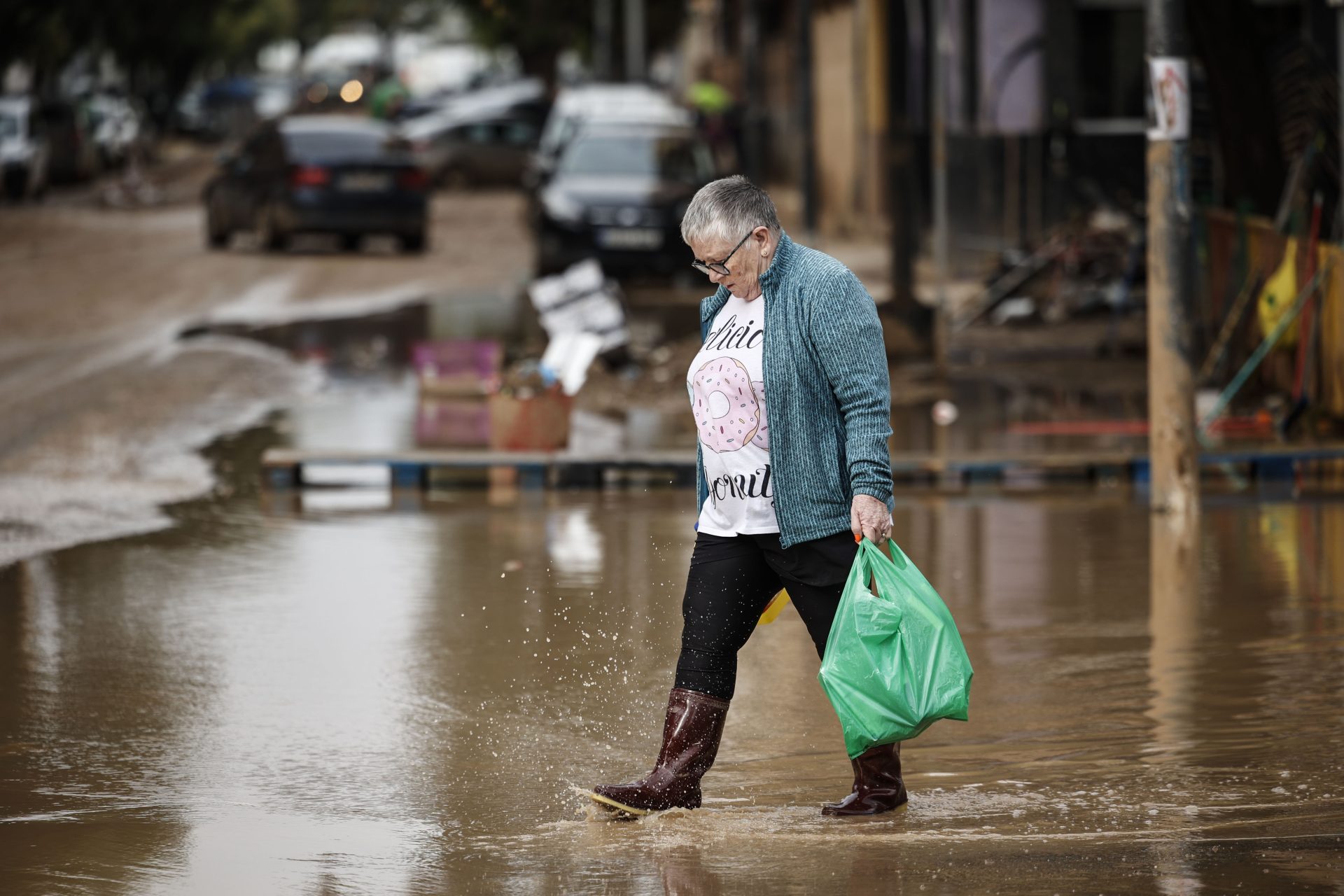 Una mujer camina esta mañana de jueves por una calle de Paiporta. AEMET ha bajado el aviso de fenómenos meteorológicos Una mujer camina por una calle de Paiporta. EFE/Biel Aliño
