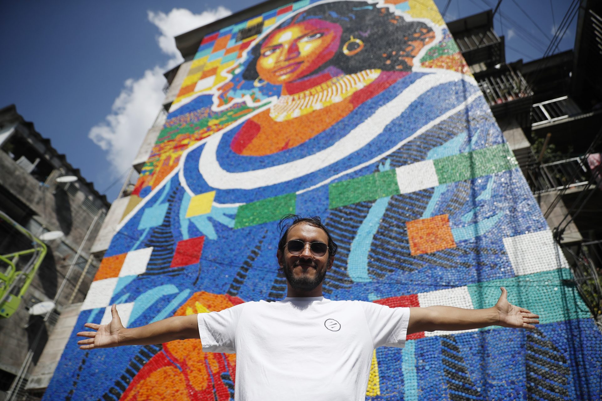 El artista venezolano Óscar Olivares posa frente a un mural elaborado con tapas plásticas este viernes, en un edificio multifamiliar en San Salvador (El Salvador). EFE/ Rodrigo Sura