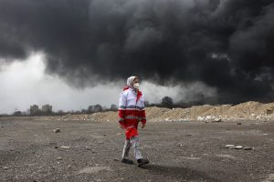 TEHRAN (IRAN (Islamic Republic Of)), 08/03/2026.- A member of Iran's Red Crescent walks as smoke still rises from Shahran Oil Refinery following last night airstrike in Tehran, Iran, 08 March 2026. A joint Israeli and US military operation continues to target multiple locations across Iran since the early hours of 28 February 2026. (Teherán) EFE/EPA/ABEDIN TAHERKENAREH
