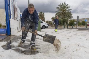 MULA (MURCIA), 08/05/2025.- Un hombre retira el granizo de la puerta de su empresa este jueves en el Polígono Industrial de El Arreaque del municipio de Mula, tras la tormenta de granizo que ha caído en los municipios de Mula, Bullas, Calasparra y Cehegín. La autovía del noroeste se ha cortado un tiempo un carril por sentido hasta que el granizo acumulado ha sido retirado con quitanieves autonómicos. EFE/Marcial Guillén
