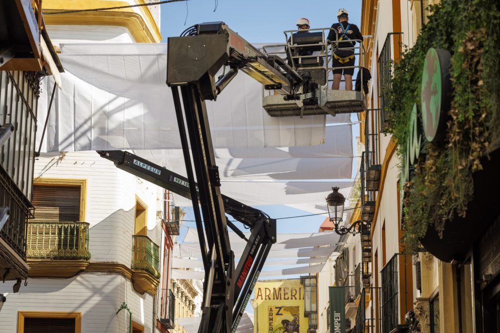 Operarios instalan en la calle Sierpes el sistema de entoldado que el Ayuntamiento de Sevilla. EFE/ Julio Muñoz