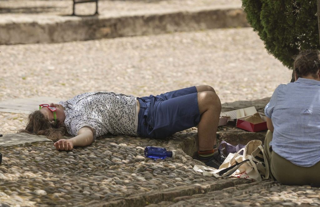 CÓRDOBA, 23/06/2026.- Un turista descansa a la sombra de un árbol en el Patio de los Naranjos, en Córdoba, este martes. El Ayuntamiento de Córdoba ha puesto en marcha este martes las medidas extraordinarias por altas temperaturas ante la activación del aviso rojo por calor extremo entre las 13.00 horas y las 21.00 horas, franja en la que se prevé "riesgo extremo". El Ayuntamiento de la capital cordobesa ha informado de que la activación de este nivel implica la puesta en marcha de actuaciones excepcionales, entre ellas la apertura de los refugios climáticos en horario de 9.00 a 21.00 horas, así como la suspensión de las actividades al aire libre durante la franja horaria en la que la Agencia Estatal de Meteorología ha decretado el nivel rojo. EFE/Rafa Alcaide