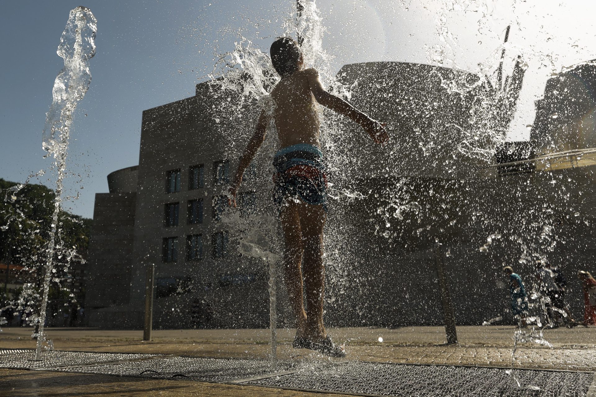 BILBAO, 23/06/2026.- Un joven se refresca en una fuente frente al Museo Guggenheim Bilbao este martes en que Euskadi afronta la segunda jornada en alarma roja por temperaturas extremas, que se espera que ronden los 40 grados en todo el territorio excepto en la costa, donde el aviso es amarillo y las temperaturas alcanzarán los 35 grados. EFE/ Miguel Toña